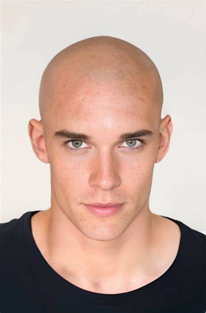 A cleaned shaved bald man in an NYC police officer uniform.