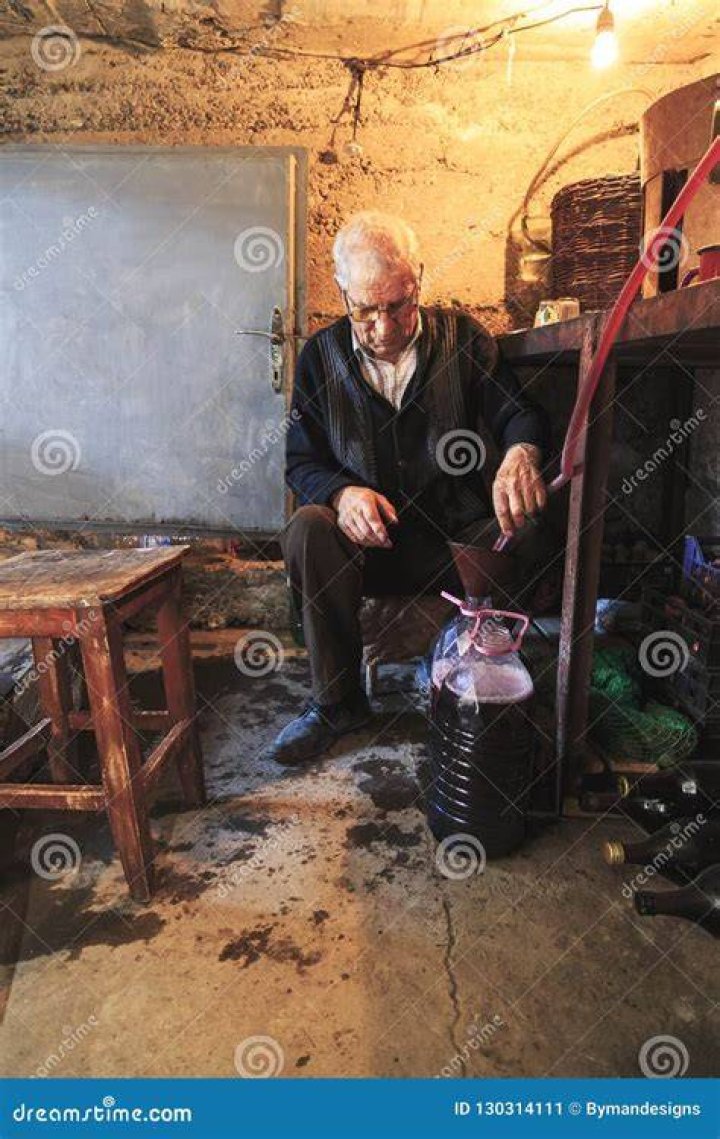 A old man stands in a tuxedo suit and bow tie.